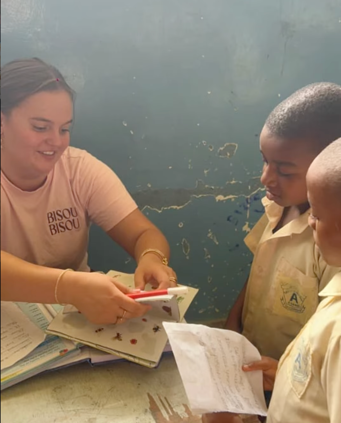 Volunteer helping students read from a workbook in a classroom